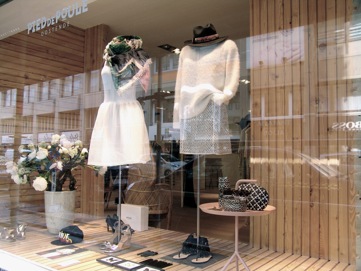 Etalage van Pied de Poule met twee lichte outfits op mannequins, schoenen, accessoires en de winkelnaam
