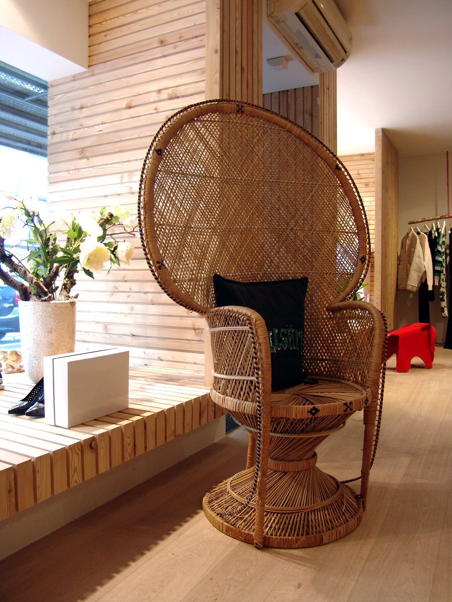 Rieten zetel met zwart kussen op een houten bank in de winkel, naast witte bloemen